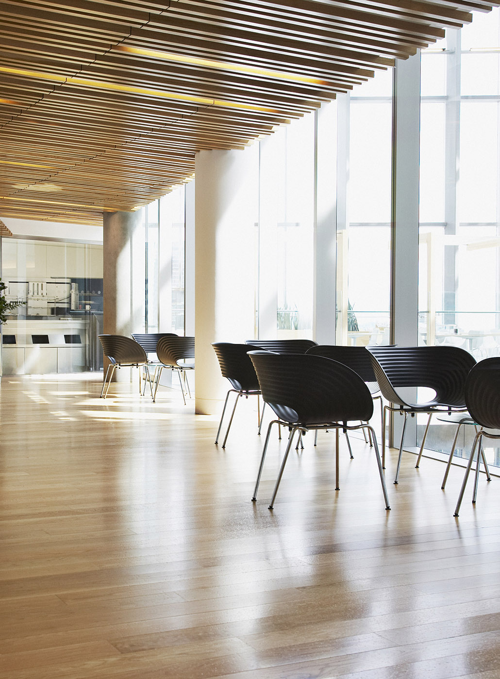 Chairs arranged on a hardwood floor in a well-lit modern office corridor.