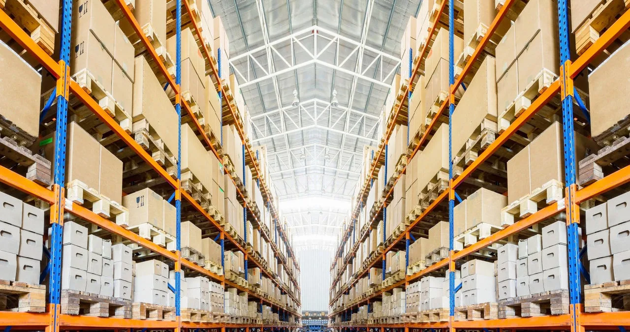 The inside of a giant shipping facility and an wide aisle with many boxes on the shelves