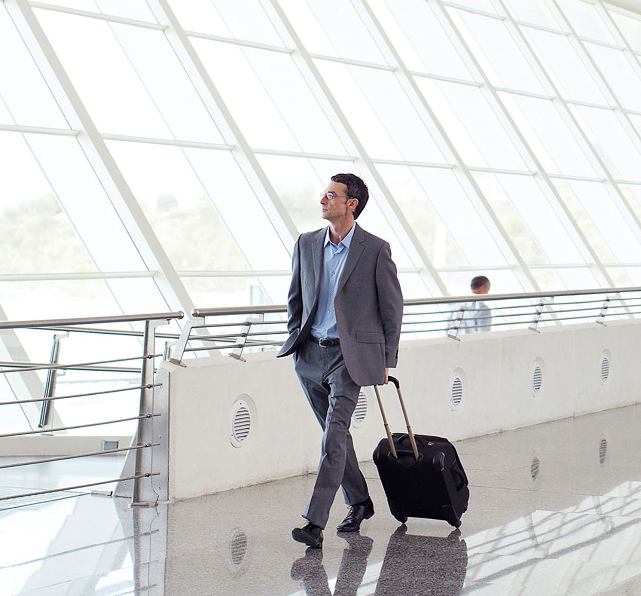 Businessman walking through airport with roller luggage