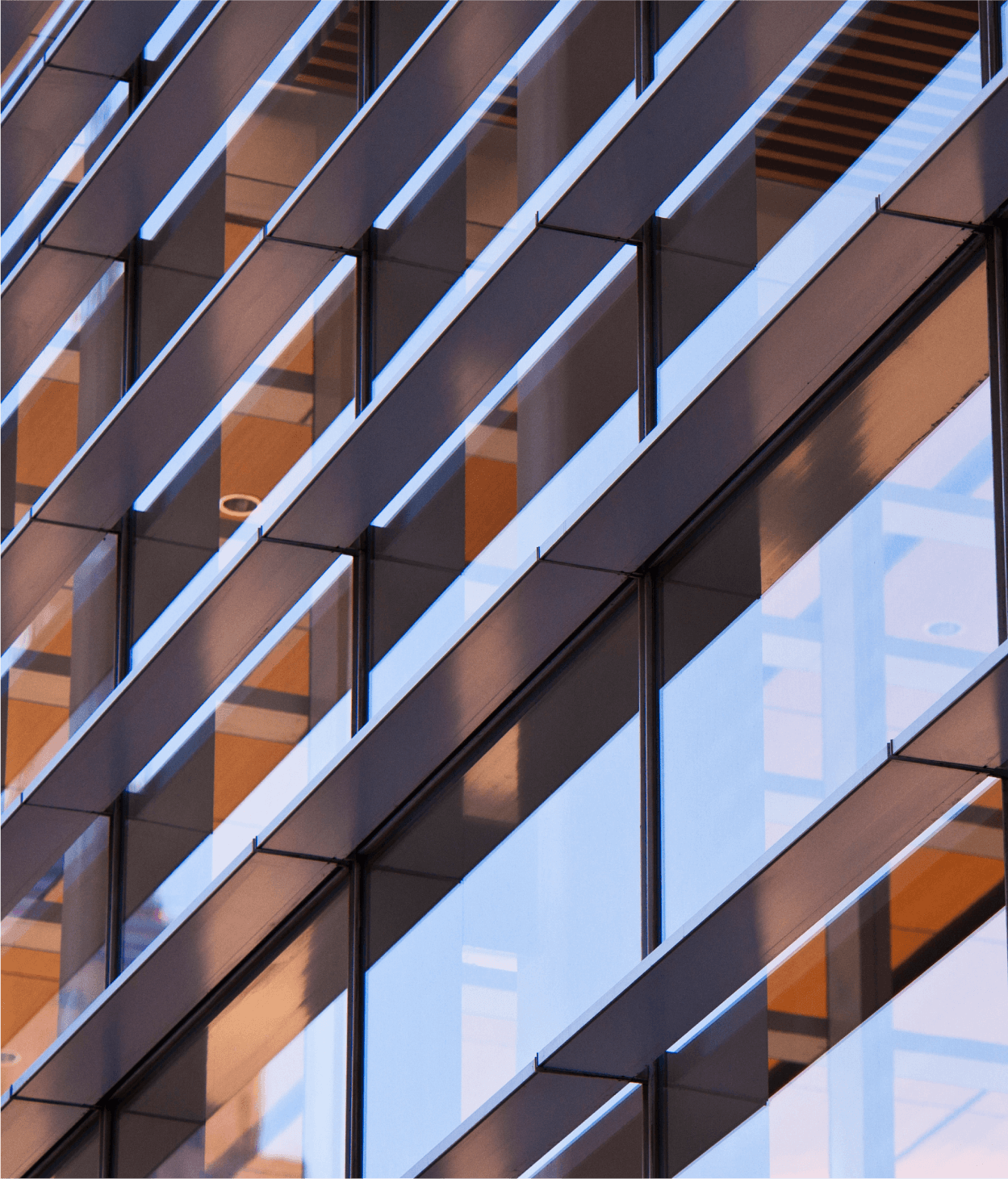 photo of the outside of an office building. The facade is covered with windows and through its reflections one could see the office's interior.