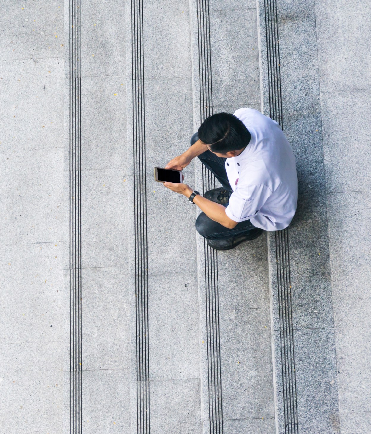 Man uses his mobile phone on stone steps