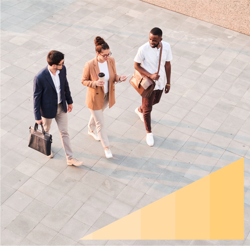 Two young men and a woman chat and walk across a stone court.