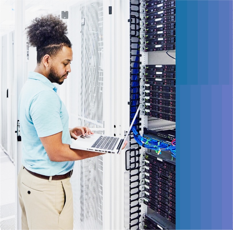 IT worker examines a server rack with his MacBook.