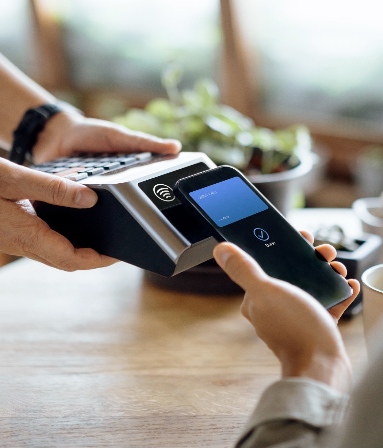 A customer using their phone on a point-of-sale device to purchase coffee.