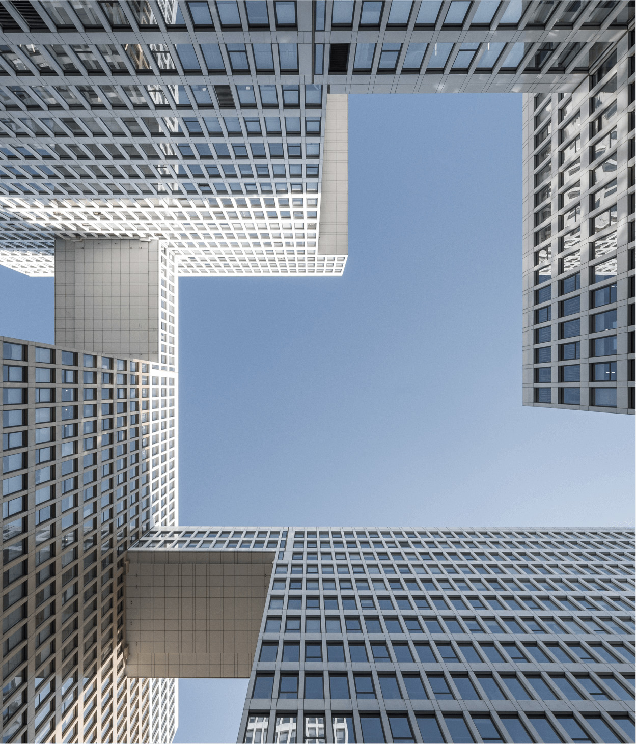 photo of skyscrapers connected by skywalks. The viewer is looking up at the skyscrapers from ground level so that the blue sky can be seen between them.
