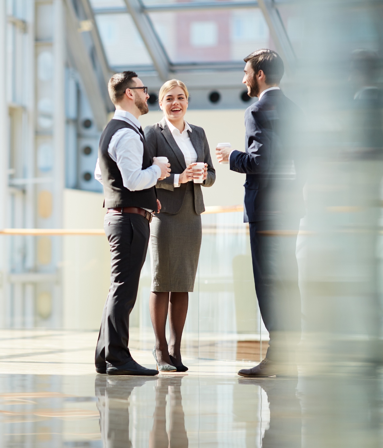 Businesspeople talk in a sunlit office lobby