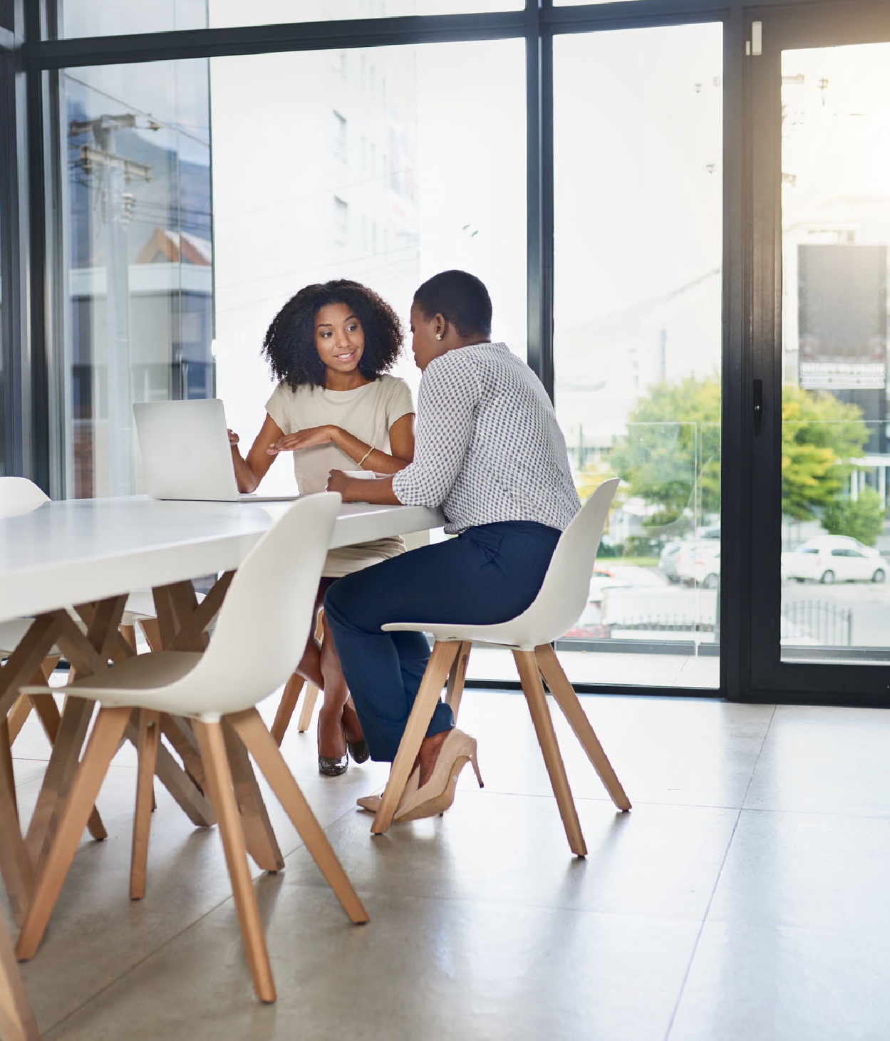 Two Black businesswomen collaborate in an office conference room.