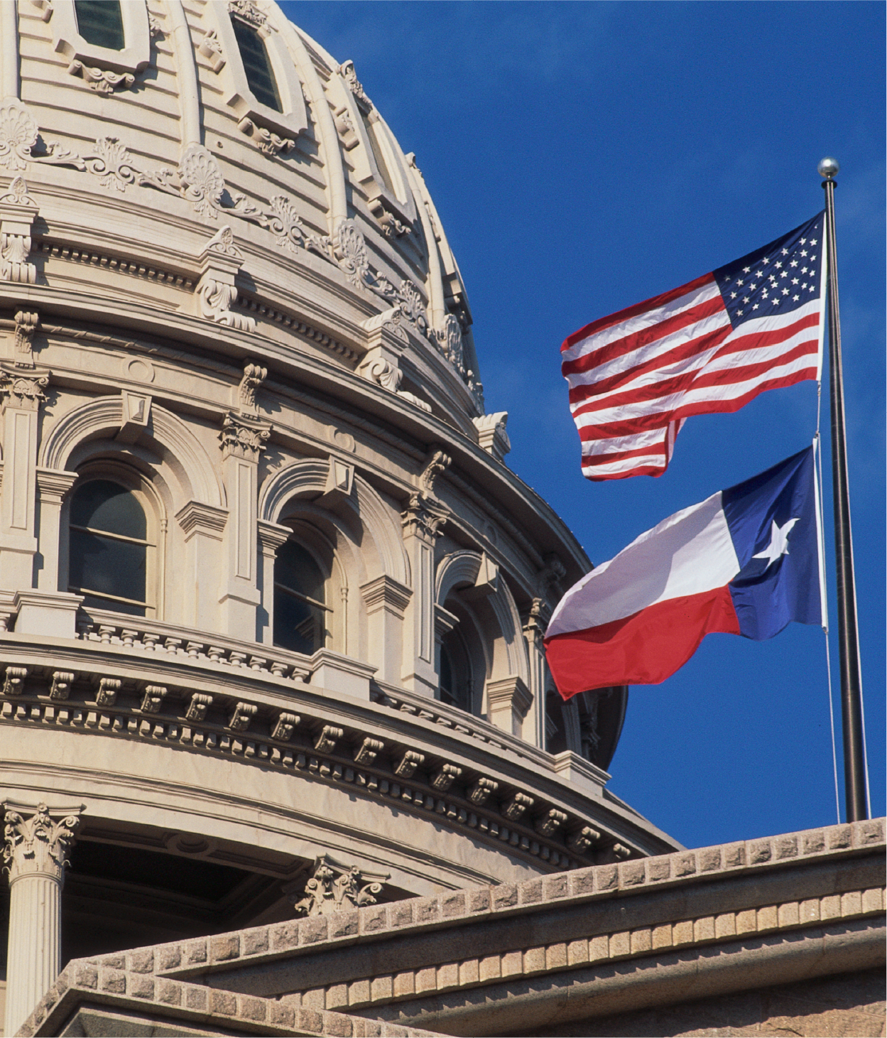 Texas capitol building with American and Texas flags blowing in the wind