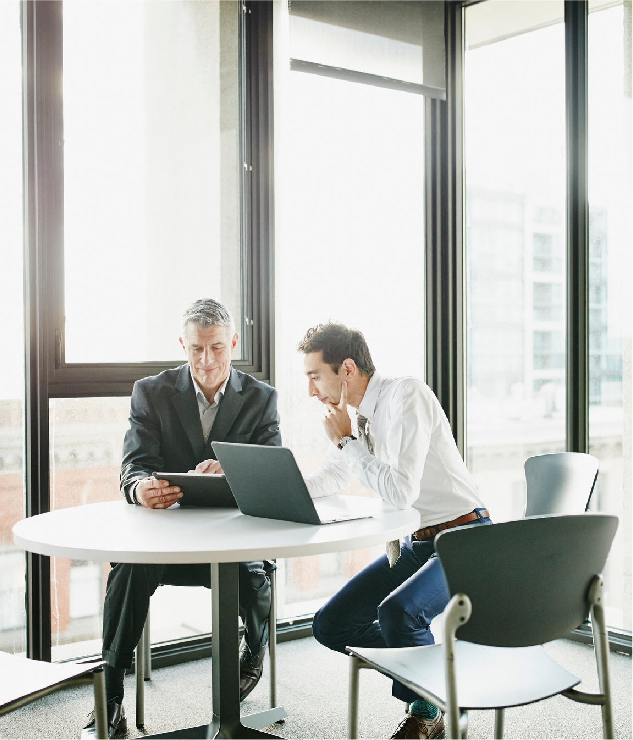 Two businessmen collaborate on a project in an office break room.