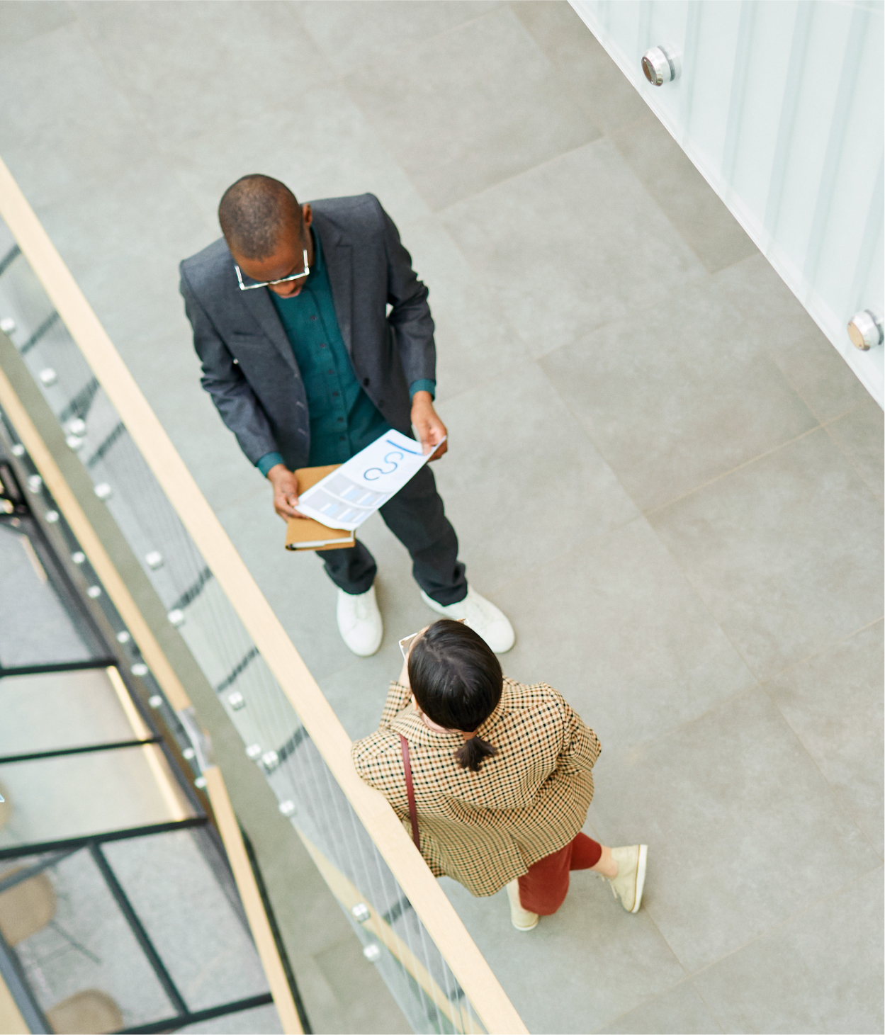 Overhead view of 2 colleagues speaking in office hallway