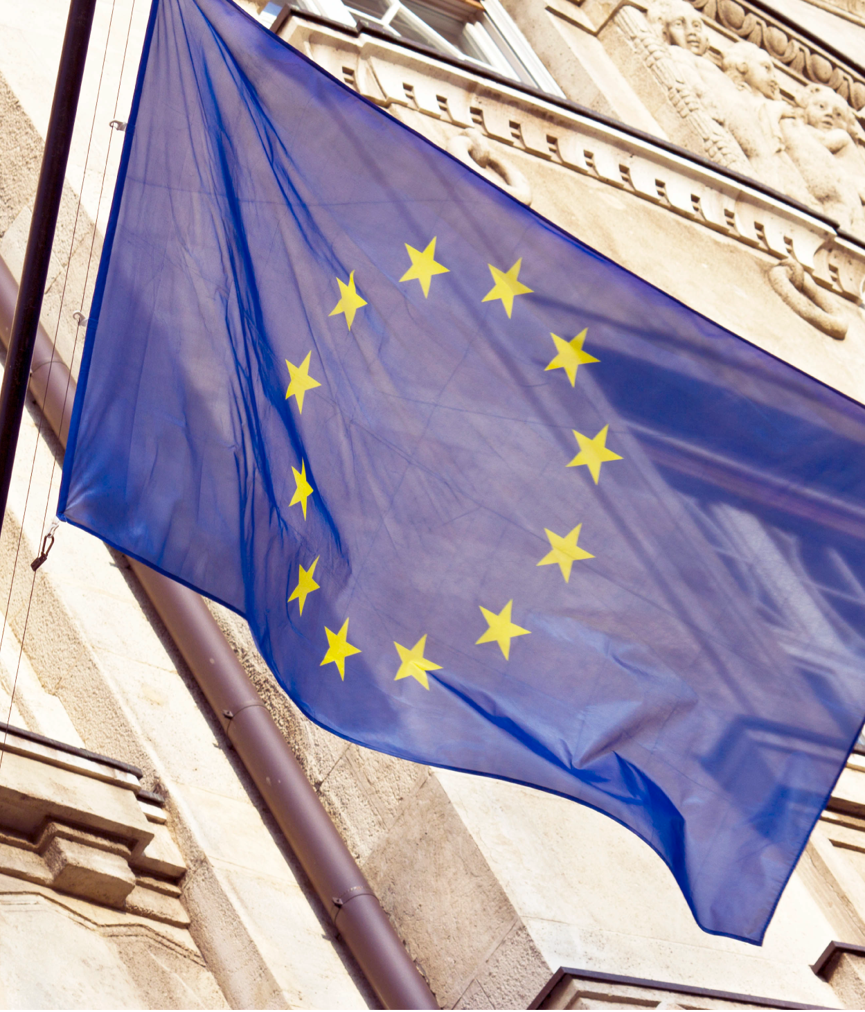 Closeup of the EU flag hanging in front of a government building.