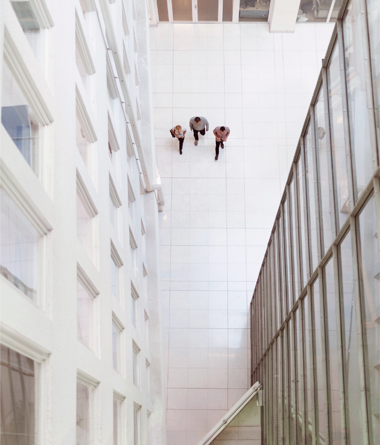 Aerial photo of three people walking down a hallway.