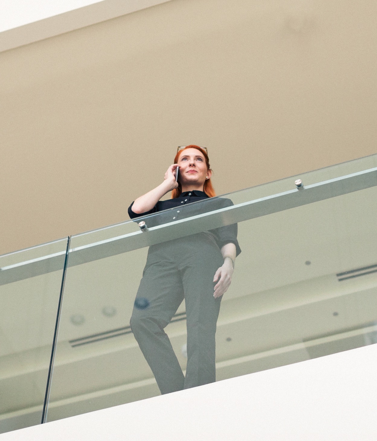 Businesswoman talks on a phone while standing on an office walkway