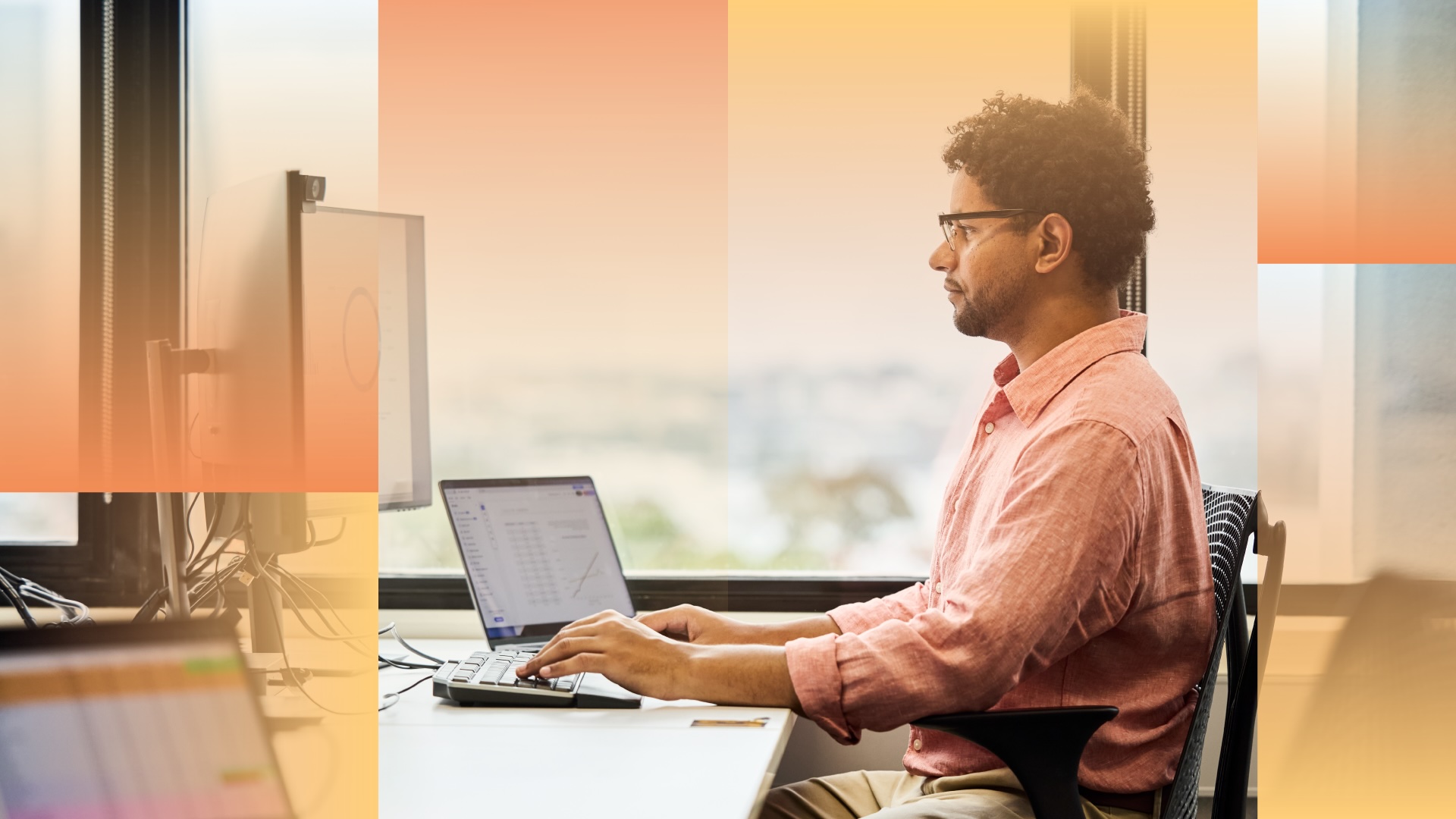 Man with glasses working on a computer at this desk