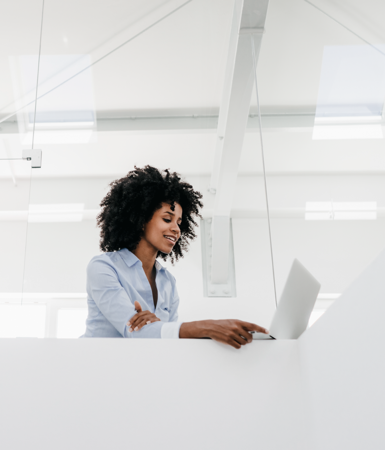 Young Black businesswoman works on her laptop in an open office.