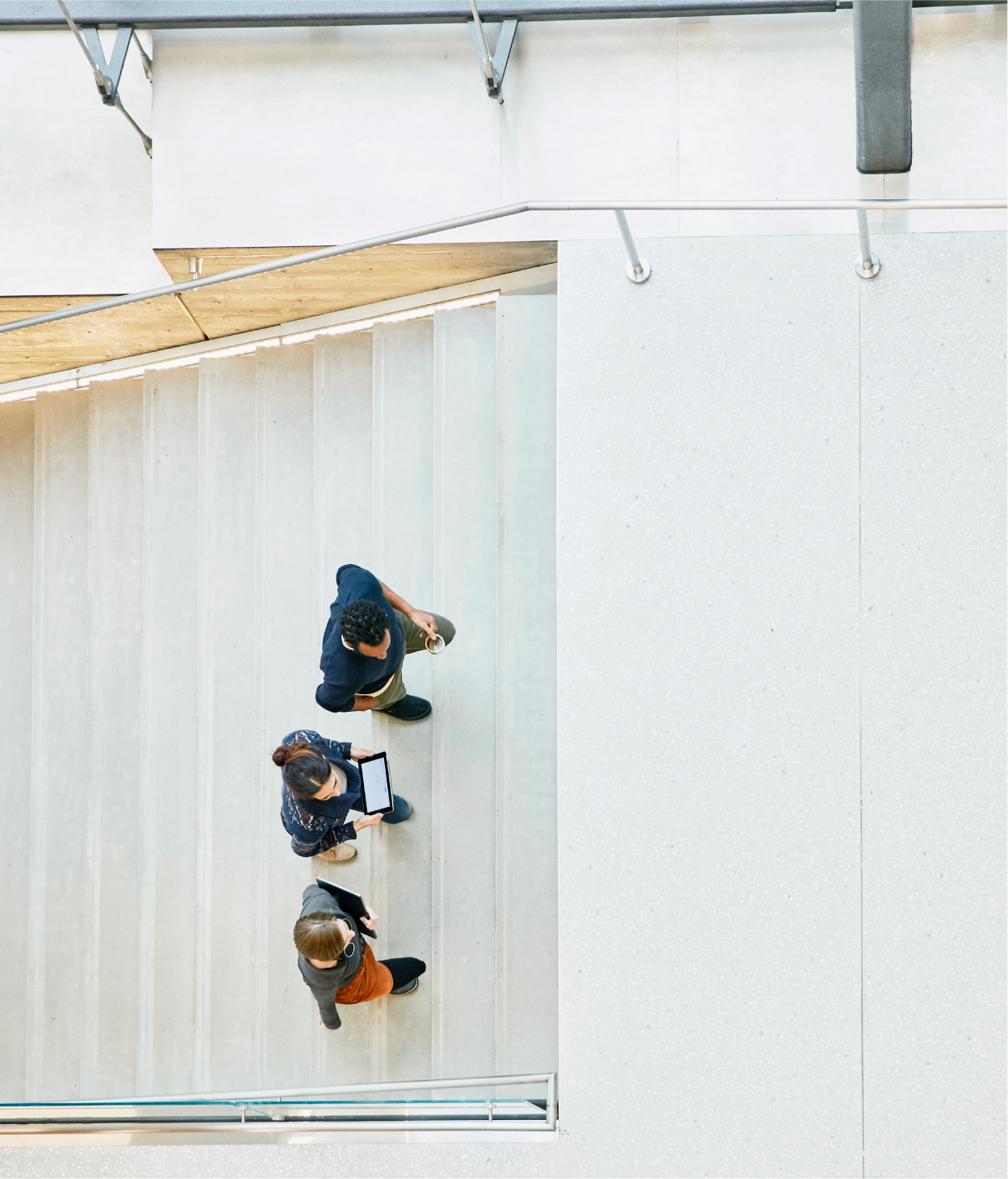 Overhead photo of three business people walking up a set of office stairs.
