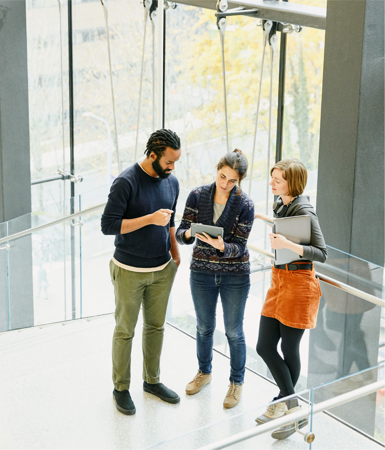 Young coworkers discuss ideas on a sunlit office stairway