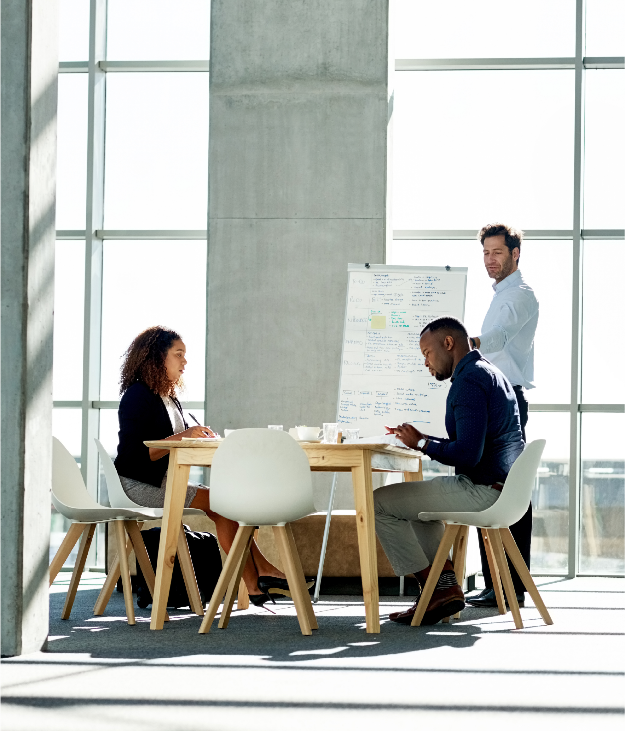 Coworkers surrounding a desk and whiteboard in a collaborative space
