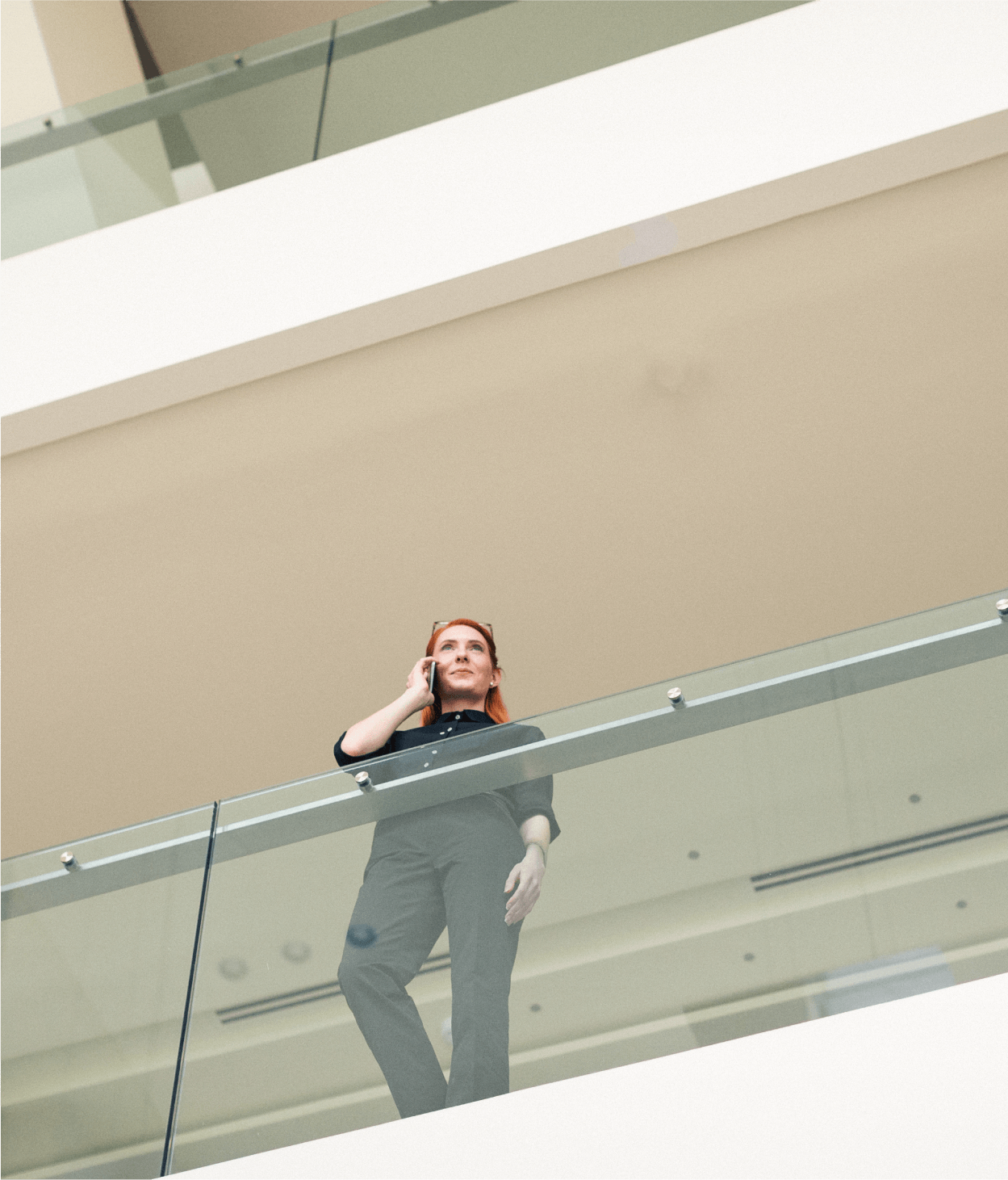 Low angle photo of woman on cell phone looking over glass railing