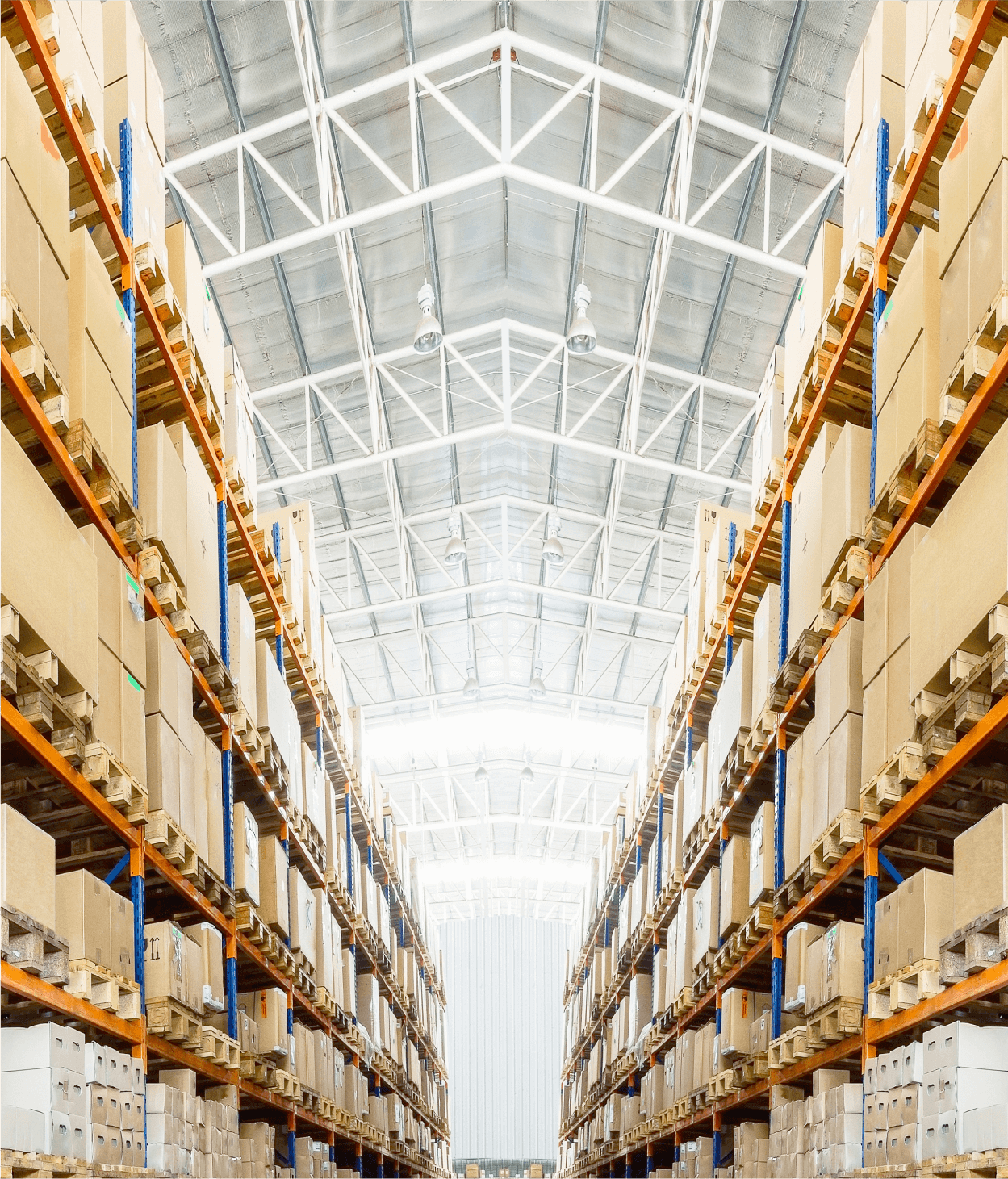 Photo looking down large industrial warehouse aisle with boxes on tall shelves