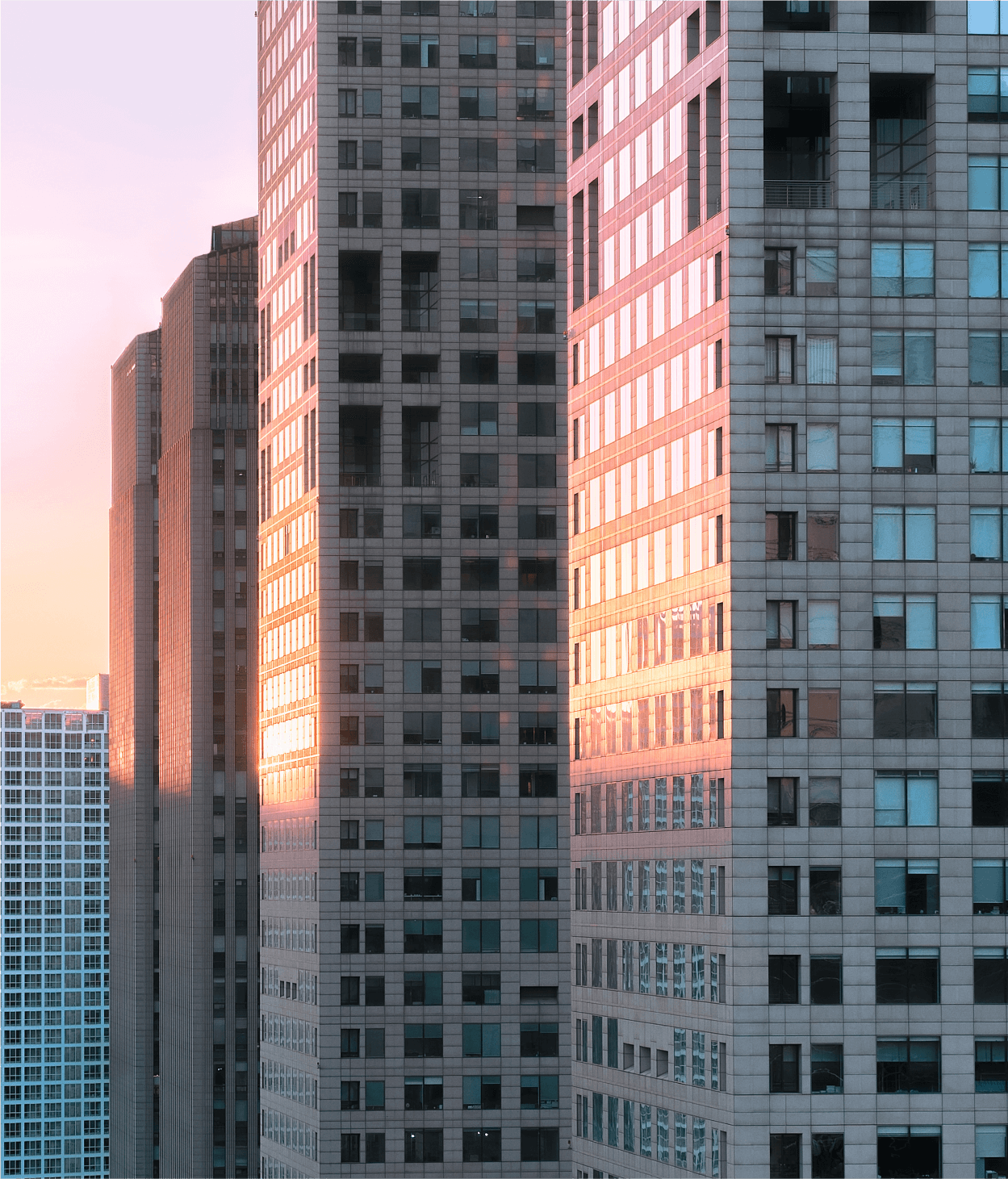 photo of a city skyline at dusk where the sun is setting behind a series of skyscapers.