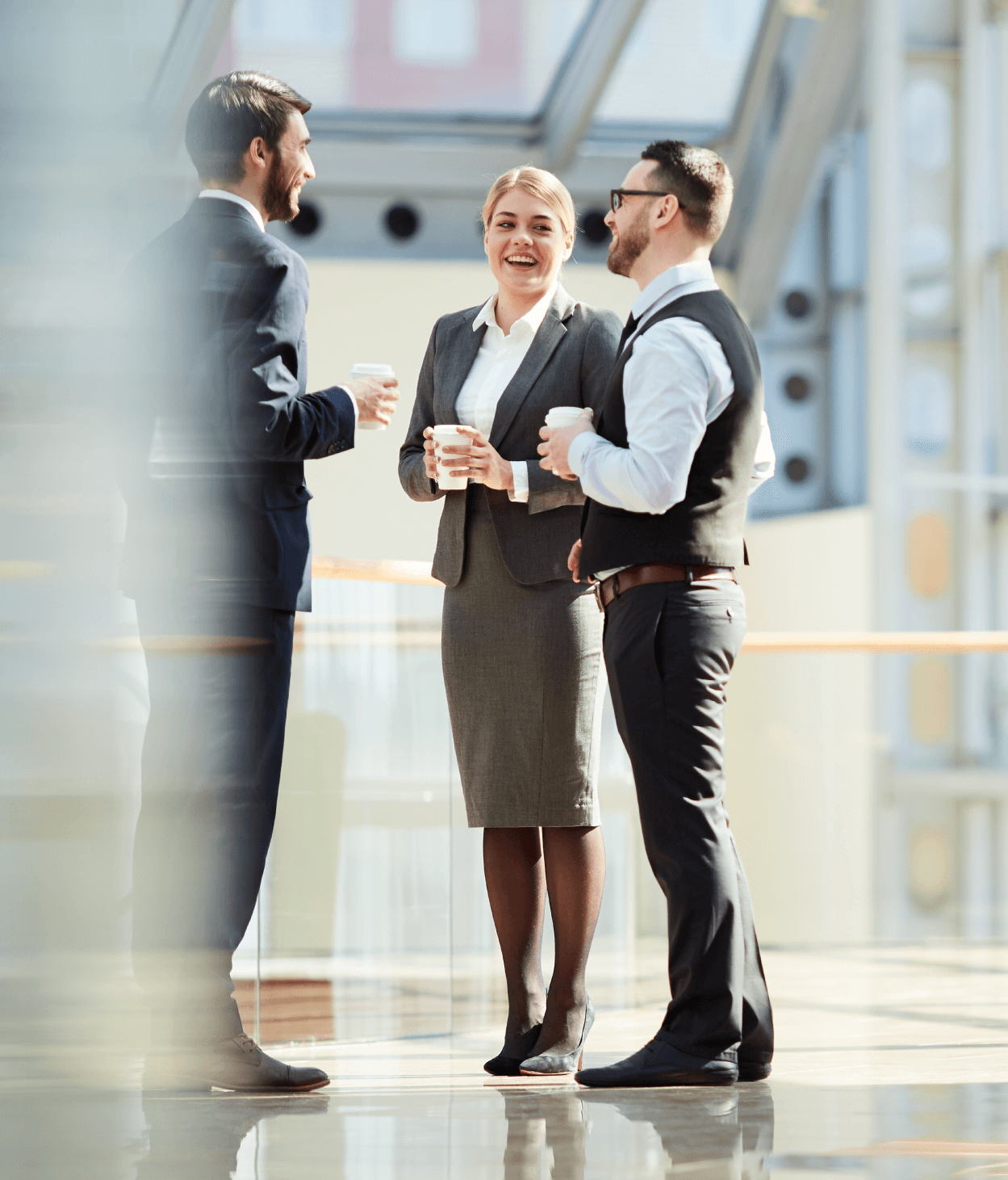 photo of a group of young business colleagues standing in a hallway and having a conversation during a coffee break.