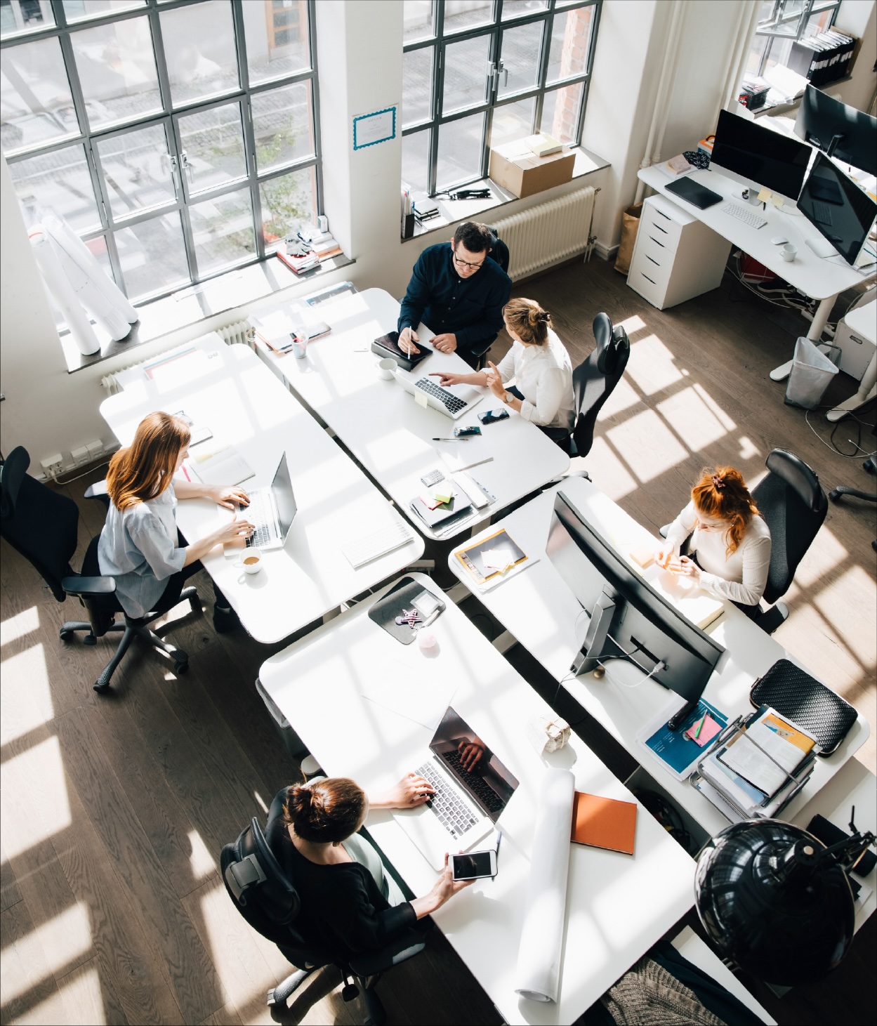 Employees working on various tasks at their office desks.