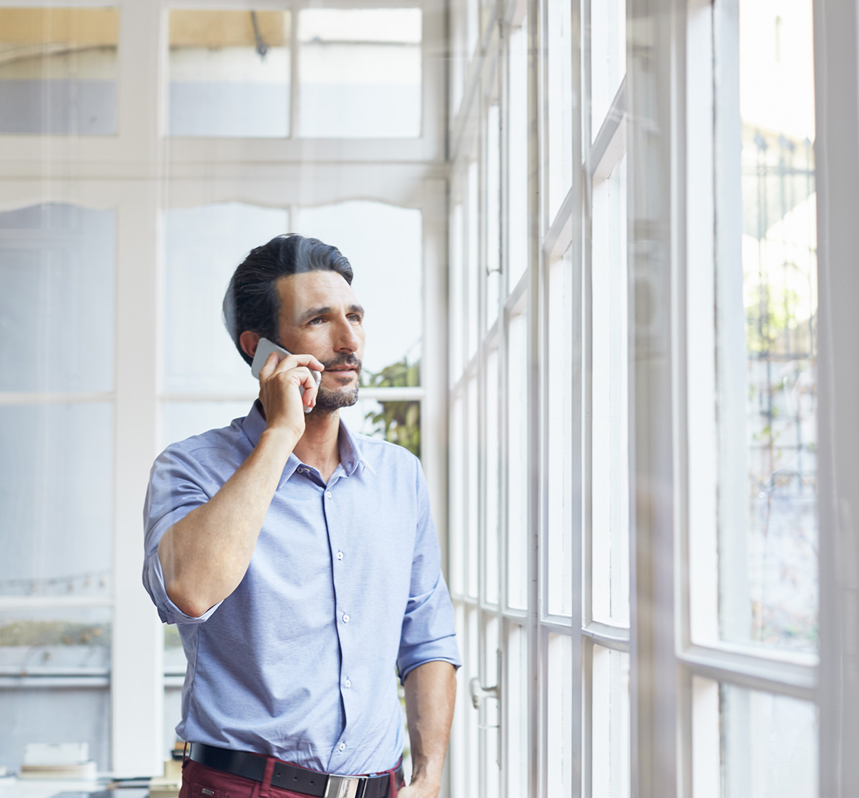 Man speaking to a moblie phone while in an office.