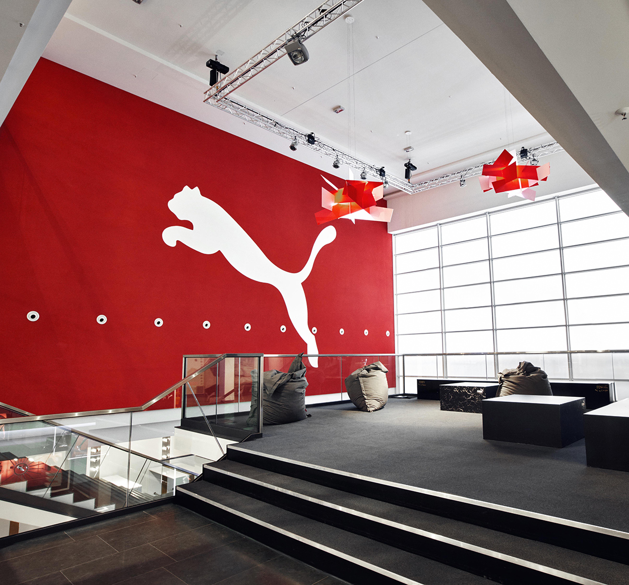 Photo of an open office space with the Puma logo on a large red wall near a seating area