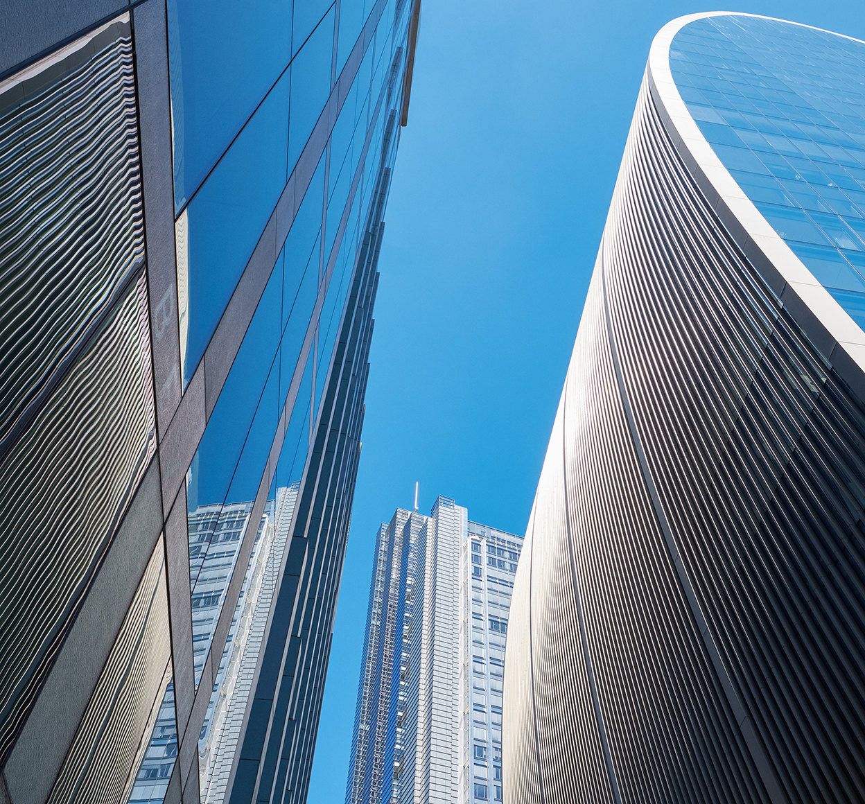 Looking up at a blue sky between a set of modern office buildings.