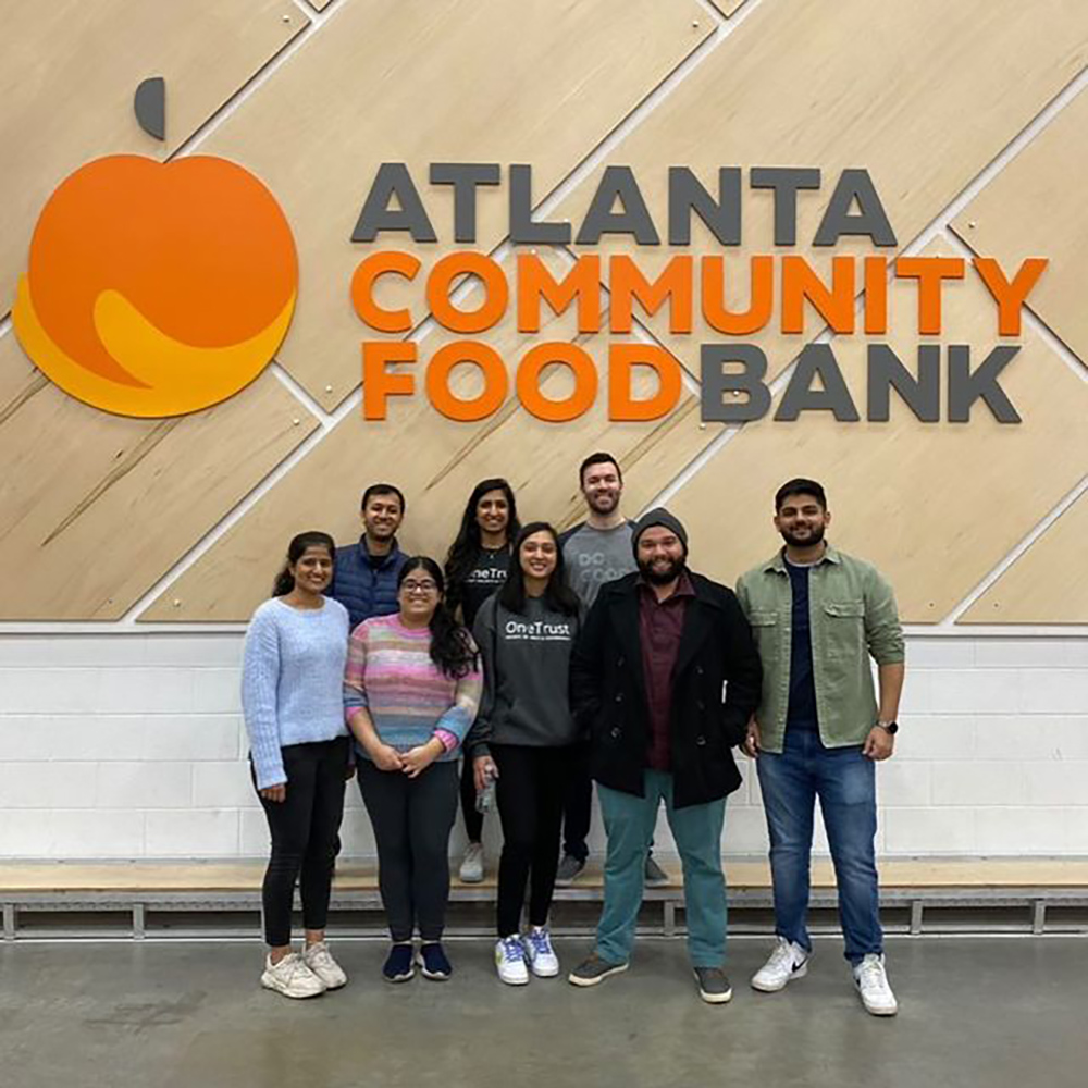 OneTrust team members pose in front of the Atlanta Community Food Bank logo