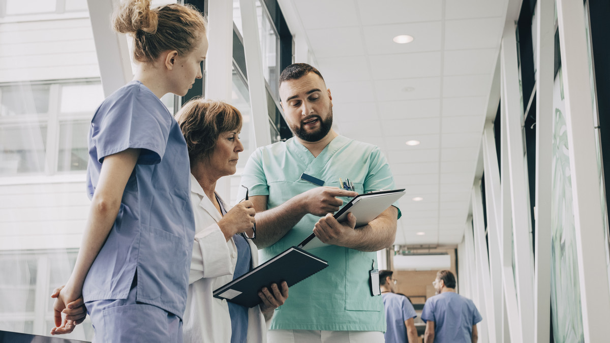 Two doctors speaking with a patient in a healthcare setting