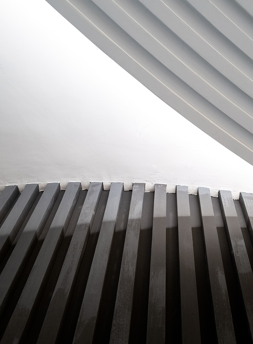 Abstract view of a concrete building, with metal bars rising up to a ceiling.