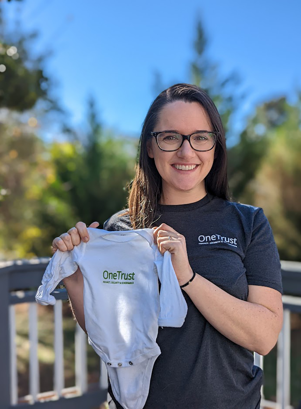 Integrante da equipe segurando uma roupa de bebê com a marca da OneTrust 