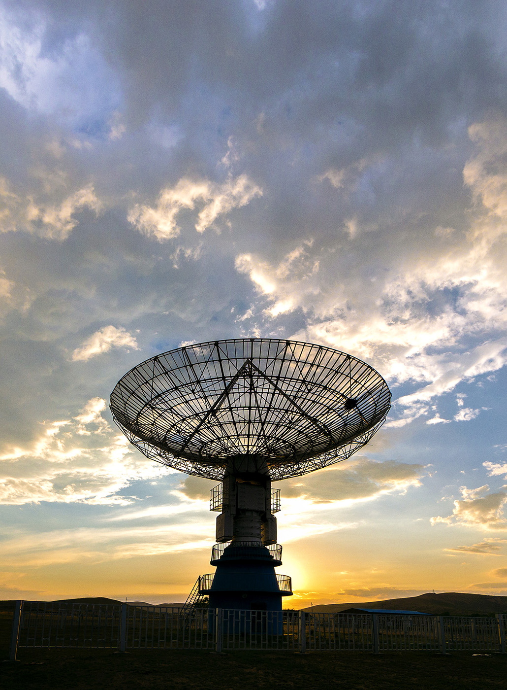 Imagen de una antena satelital con el atardecer por detrás.