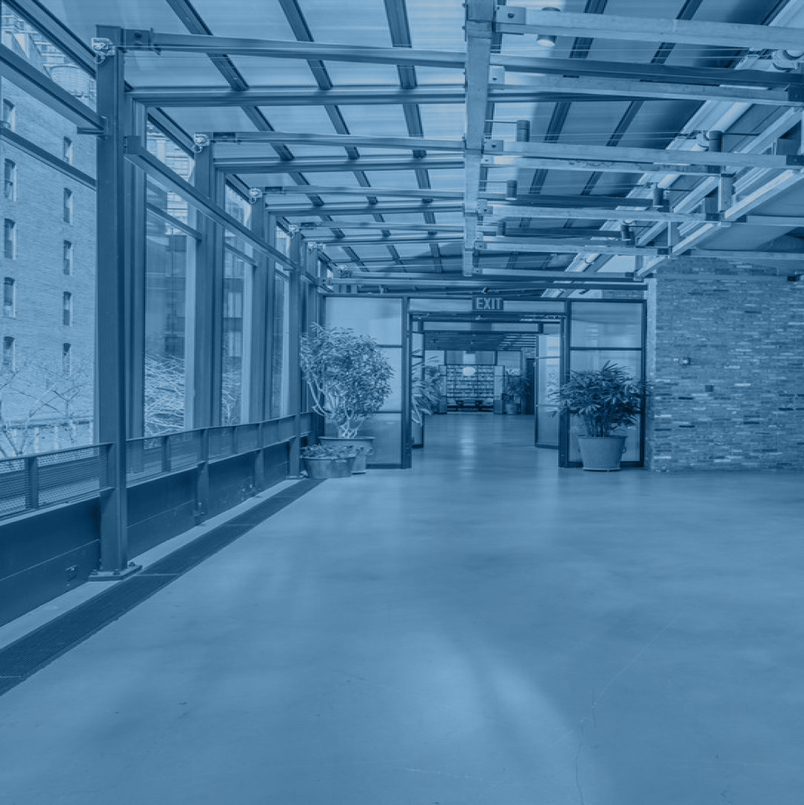 Indoor view of venue for TrustWeek New York showing an open air space with large windows, brick, and plants