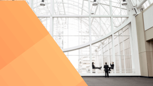 Three people in business suit attire chat by windows in a modern building with an orange parallelogram step gradient towards the left of the image.